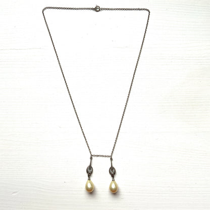 A silver necklace featuring delicate marcasite details and ivory teardrop pearls. マーカサイトの繊細なディテールとアイボリーのティアドロップパールが揺れるシルバーネックレス。