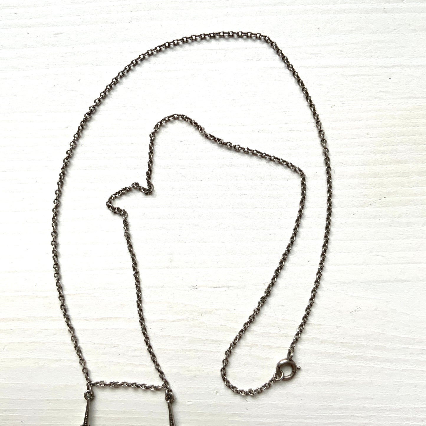 A silver necklace featuring delicate marcasite details and ivory teardrop pearls. マーカサイトの繊細なディテールとアイボリーのティアドロップパールが揺れるシルバーネックレス。