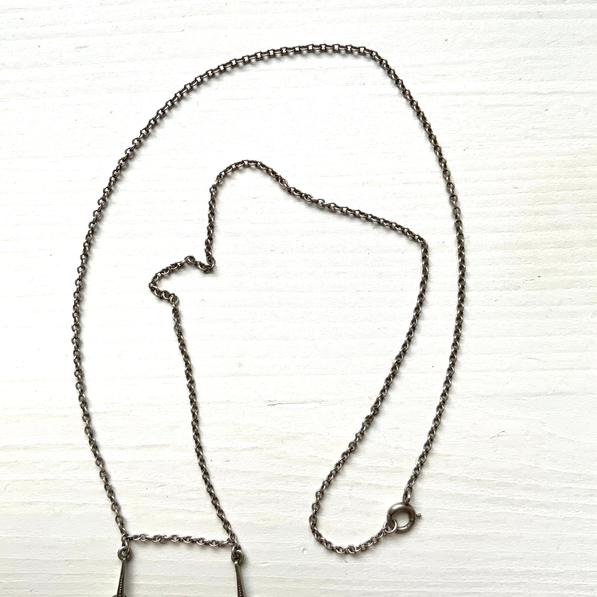 A silver necklace featuring delicate marcasite details and ivory teardrop pearls. マーカサイトの繊細なディテールとアイボリーのティアドロップパールが揺れるシルバーネックレス。