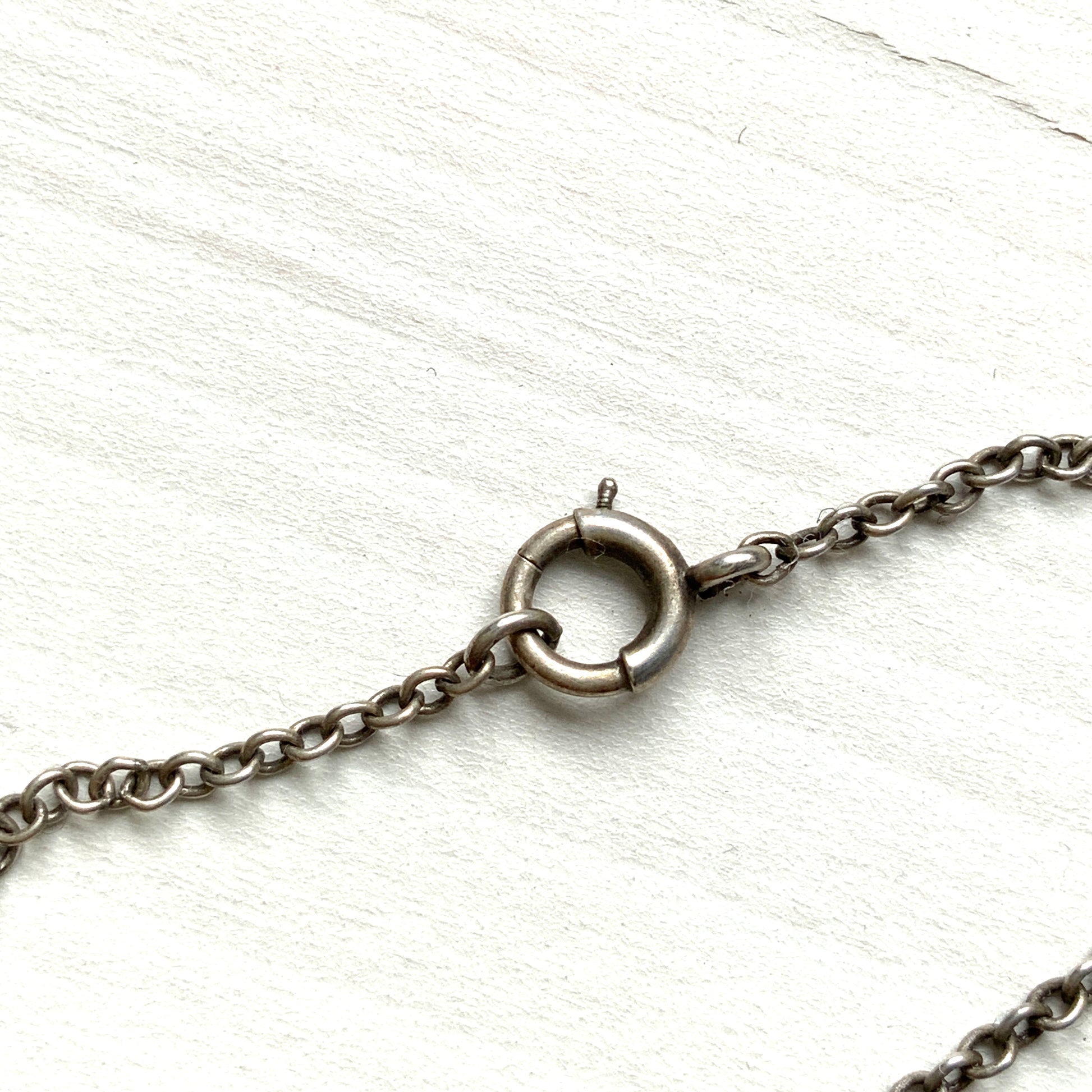 A silver necklace featuring delicate marcasite details and ivory teardrop pearls. マーカサイトの繊細なディテールとアイボリーのティアドロップパールが揺れるシルバーネックレス。