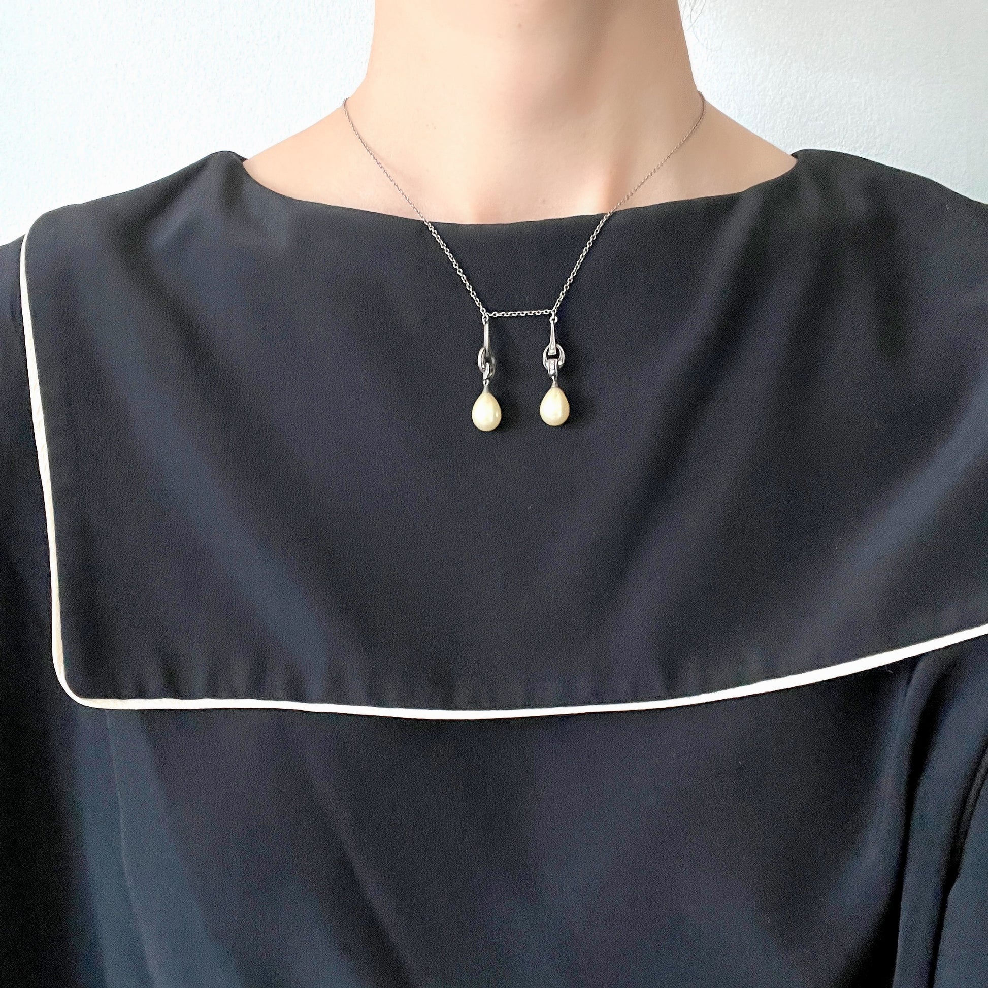 A silver necklace featuring delicate marcasite details and ivory teardrop pearls. マーカサイトの繊細なディテールとアイボリーのティアドロップパールが揺れるシルバーネックレス。