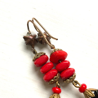 Earrings featuring stacked red glass beads with a black barrel-shaped drop that sways gracefully below. 重ねられた粒状のレッドガラスの下で、黒のバレル型ガラスが揺れるピアス。
