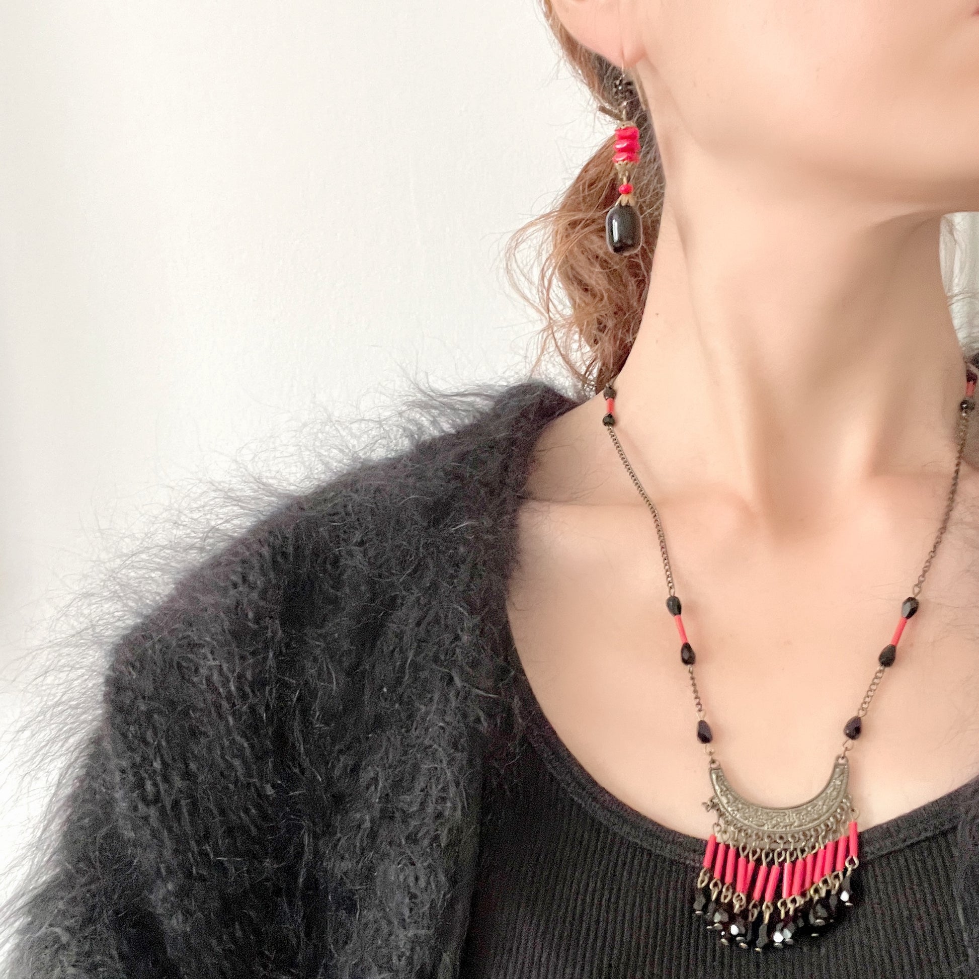 Earrings featuring stacked red glass beads with a black barrel-shaped drop that sways gracefully below. 重ねられた粒状のレッドガラスの下で、黒のバレル型ガラスが揺れるピアス。