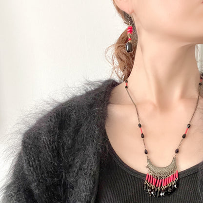 Earrings featuring stacked red glass beads with a black barrel-shaped drop that sways gracefully below. 重ねられた粒状のレッドガラスの下で、黒のバレル型ガラスが揺れるピアス。