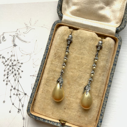 Screw earrings featuring a silver-tone leaf with a champagne gold teardrop pearl glass dangling from the tip. シルバートーンのリーフの先にシャンパンゴールドカラーのティアドロップグラスパールが揺れるスクリューイヤリング。