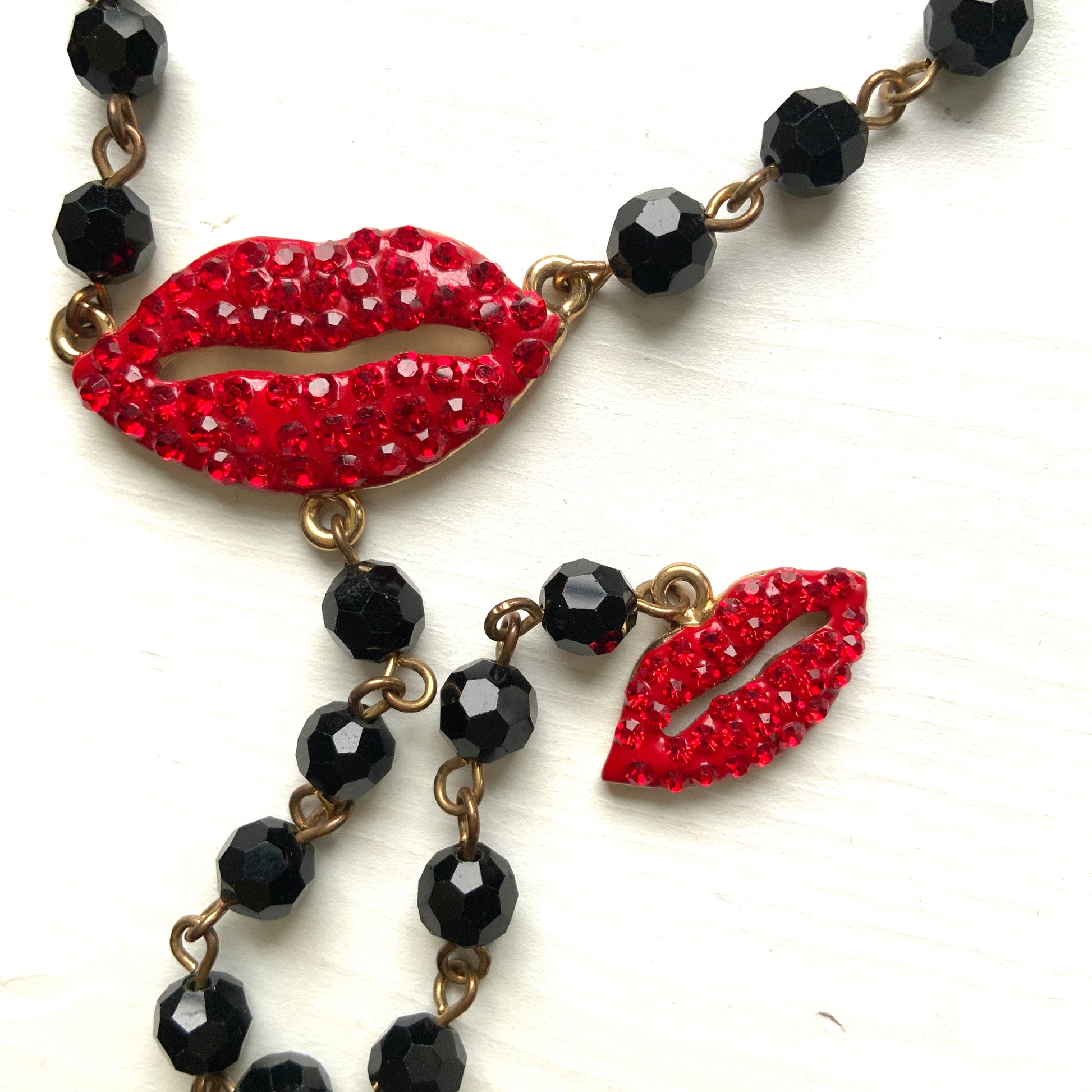 Rosary-style necklace by Butler & Wilson, featuring vivid red lips on a strand of black glass beads.  ブラックグラスビーズに真っ赤な唇をあしらった、バトラー＆ウィルソンのロザリオネックレス。