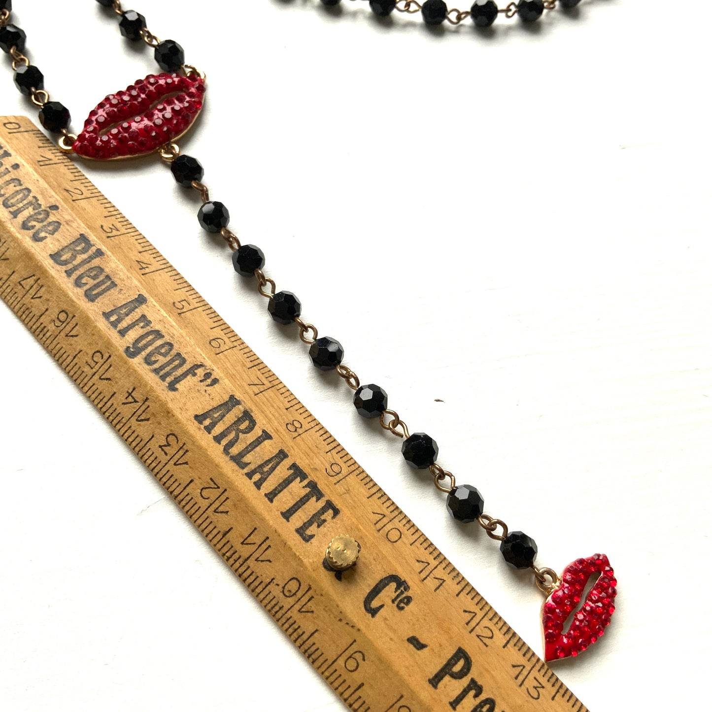 Rosary-style necklace by Butler & Wilson, featuring vivid red lips on a strand of black glass beads.  ブラックグラスビーズに真っ赤な唇をあしらった、バトラー＆ウィルソンのロザリオネックレス。