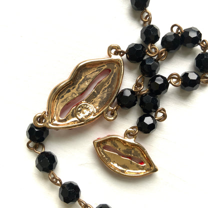 Rosary-style necklace by Butler & Wilson, featuring vivid red lips on a strand of black glass beads.  ブラックグラスビーズに真っ赤な唇をあしらった、バトラー＆ウィルソンのロザリオネックレス。