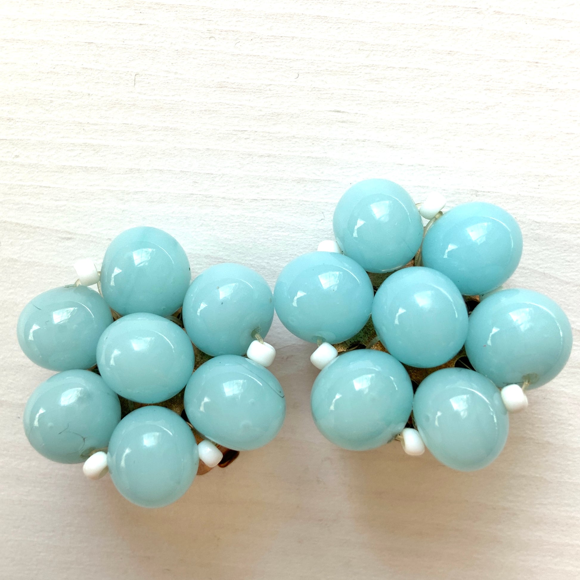 These clip-on earrings feature a cluster of soft pastel blue glass beads, accented with small milk glass beads nestled in between. 淡いパステルブルーのガラスビーズが集まったクリップイヤリング。