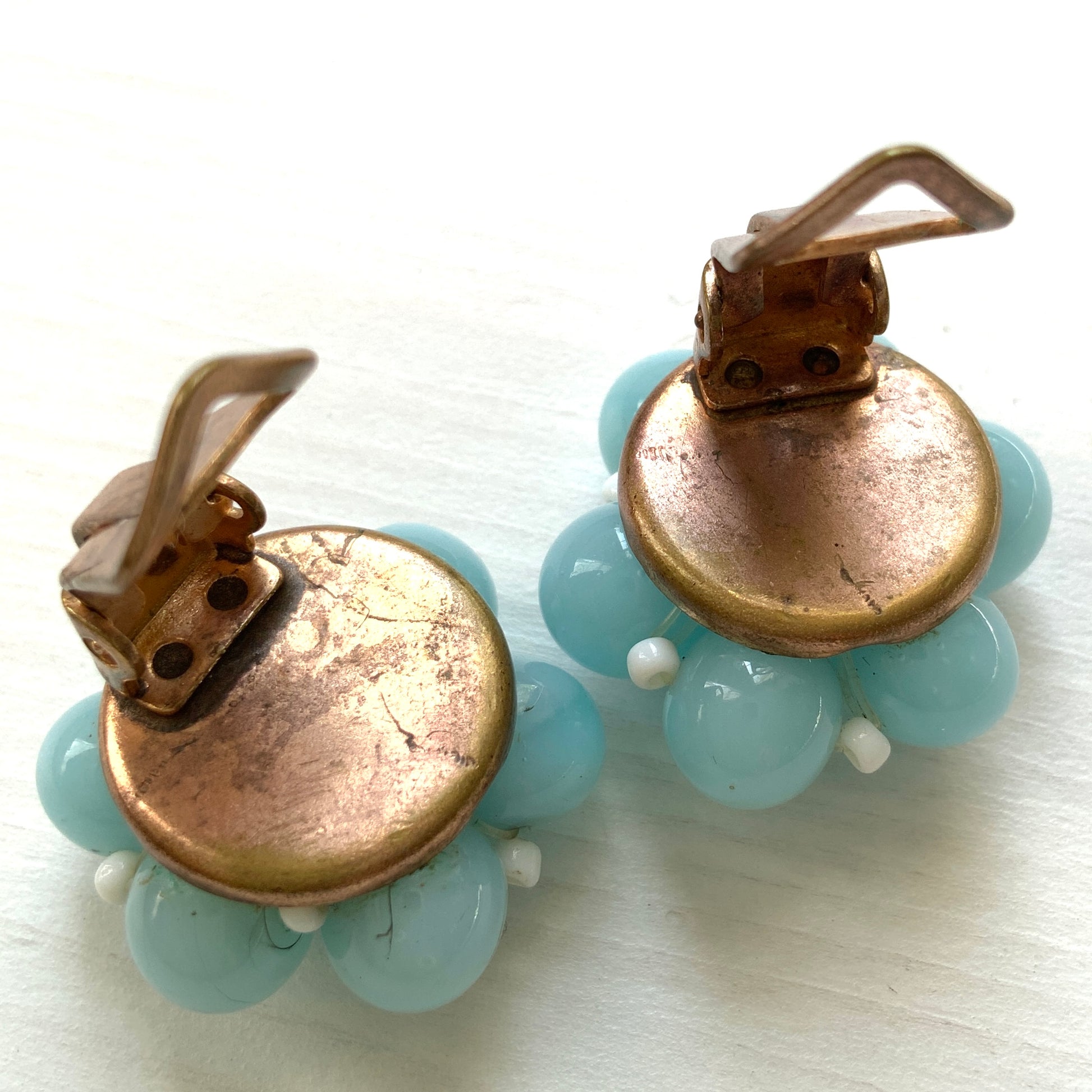These clip-on earrings feature a cluster of soft pastel blue glass beads, accented with small milk glass beads nestled in between. 淡いパステルブルーのガラスビーズが集まったクリップイヤリング。