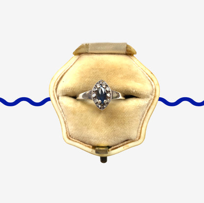 A vintage silver ring featuring a deep blue spinel reminiscent of the ocean, surrounded by delicate clear stones. 深い海のようなブルースピネルを、小さなクリアストーンで囲んだヴィンテージのシルバーリング。