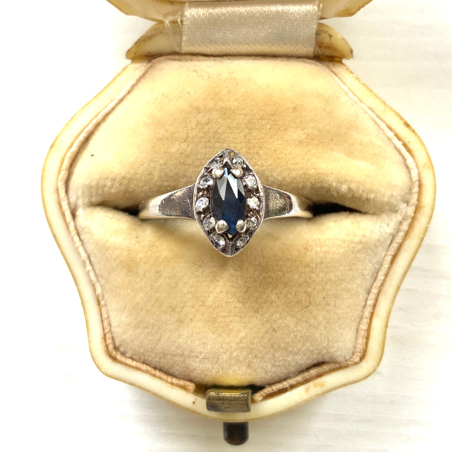 A vintage silver ring featuring a deep blue spinel reminiscent of the ocean, surrounded by delicate clear stones. 深い海のようなブルースピネルを、小さなクリアストーンで囲んだヴィンテージのシルバーリング。