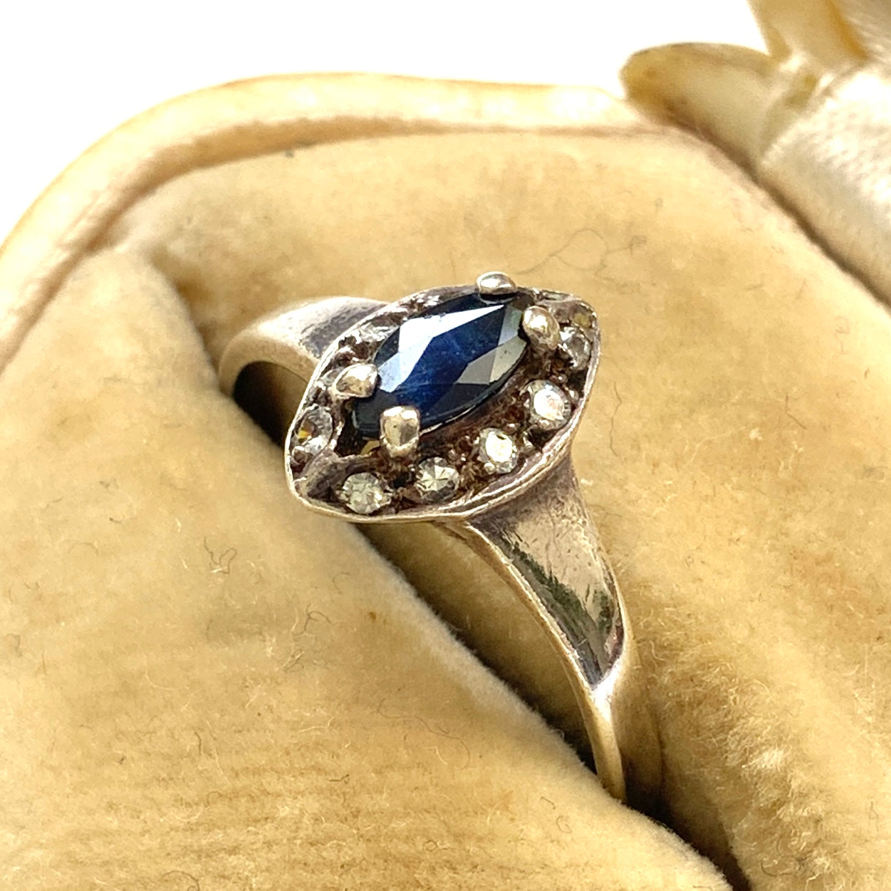 A vintage silver ring featuring a deep blue spinel reminiscent of the ocean, surrounded by delicate clear stones. 深い海のようなブルースピネルを、小さなクリアストーンで囲んだヴィンテージのシルバーリング。