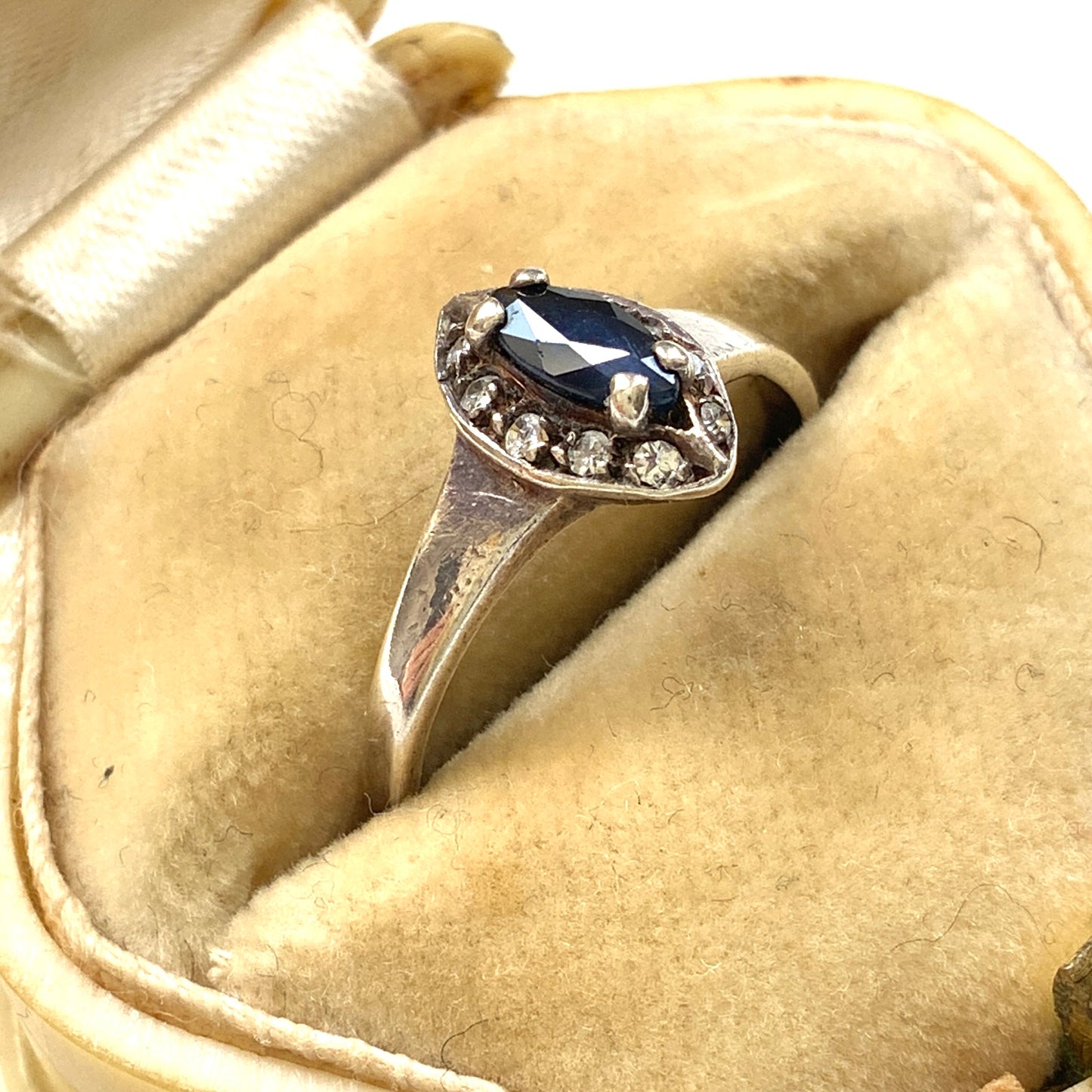 A vintage silver ring featuring a deep blue spinel reminiscent of the ocean, surrounded by delicate clear stones. 深い海のようなブルースピネルを、小さなクリアストーンで囲んだヴィンテージのシルバーリング。