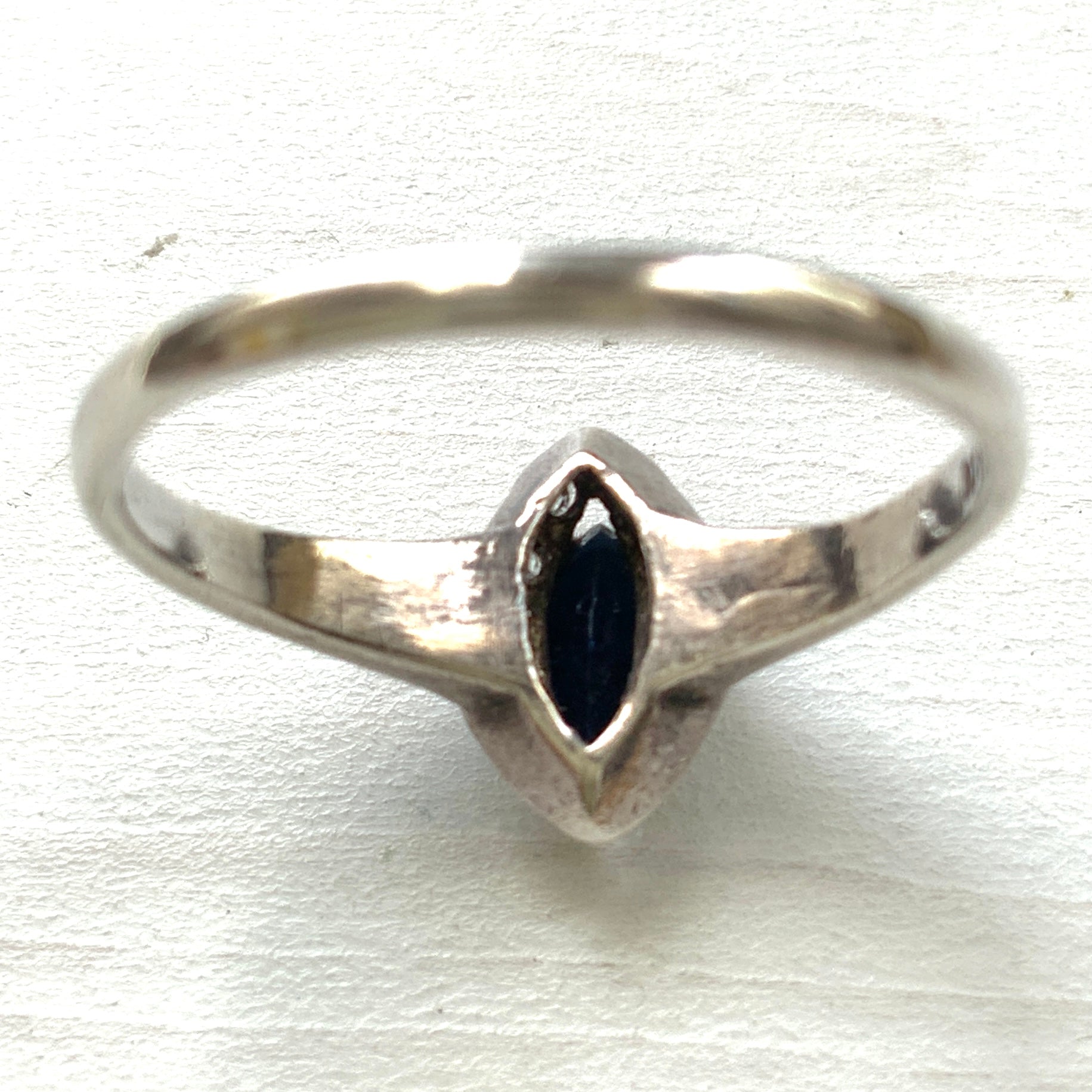 A vintage silver ring featuring a deep blue spinel reminiscent of the ocean, surrounded by delicate clear stones. 深い海のようなブルースピネルを、小さなクリアストーンで囲んだヴィンテージのシルバーリング。