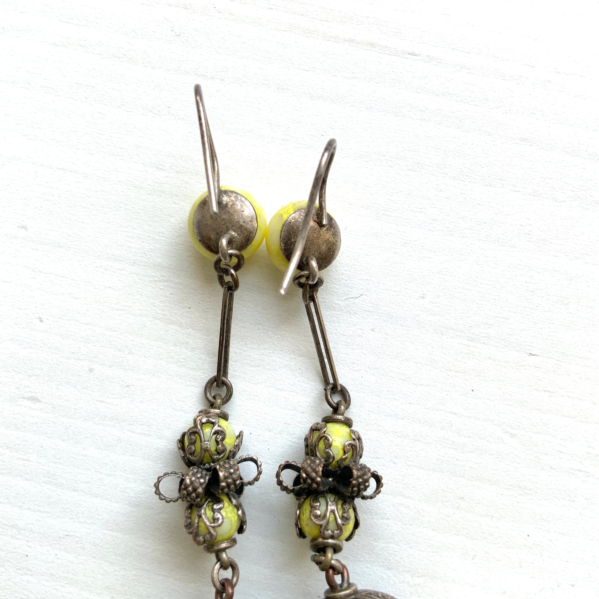Uranium glass earrings featuring vibrant neon yellow glass beads with unique mottled patterns. 鮮やかなネオンイエローのウランガラスを使用したピアス。