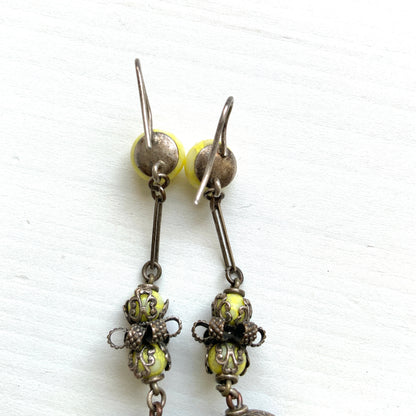 Uranium glass earrings featuring vibrant neon yellow glass beads with unique mottled patterns. 鮮やかなネオンイエローのウランガラスを使用したピアス。