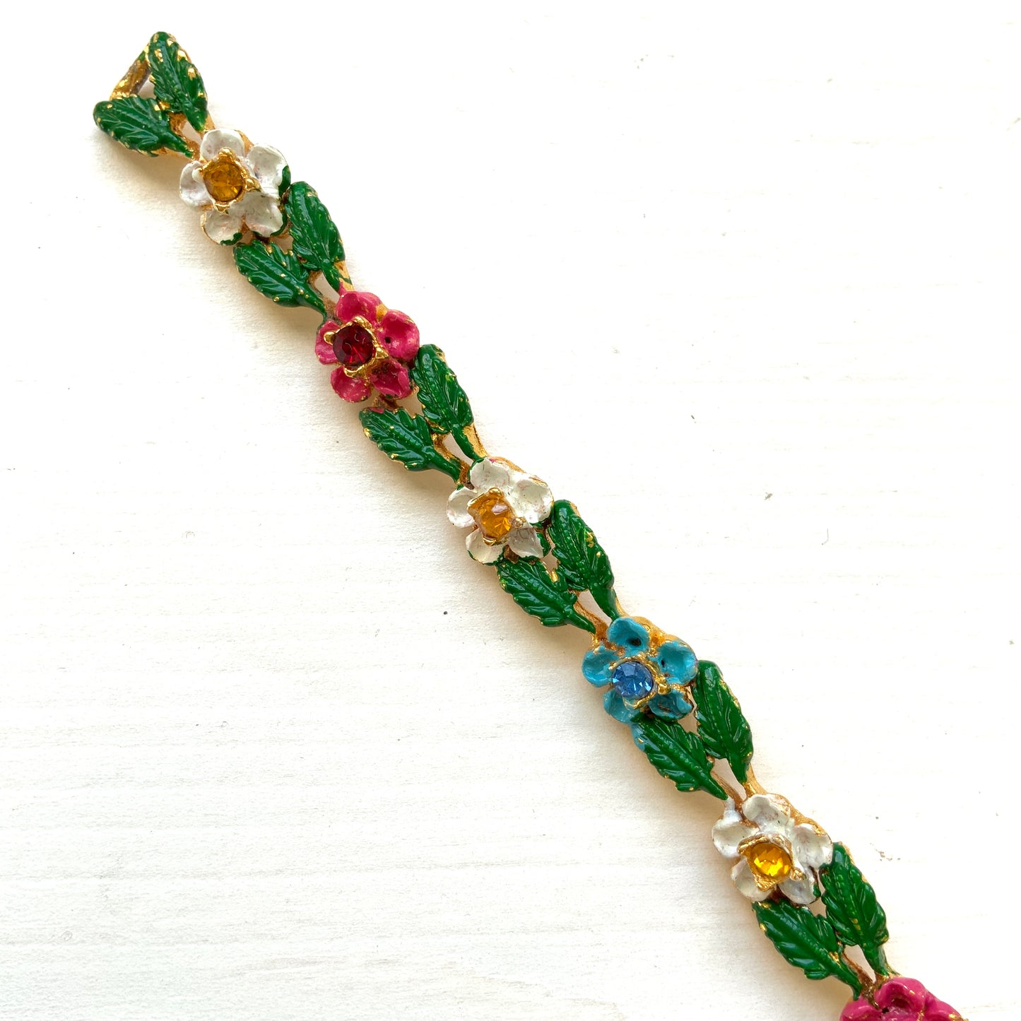 A delicate enamel bracelet adorned with rows of pink, pale blue and white flowers. ピンク、水色、白のお花が並んだエナメルのブレスレット。