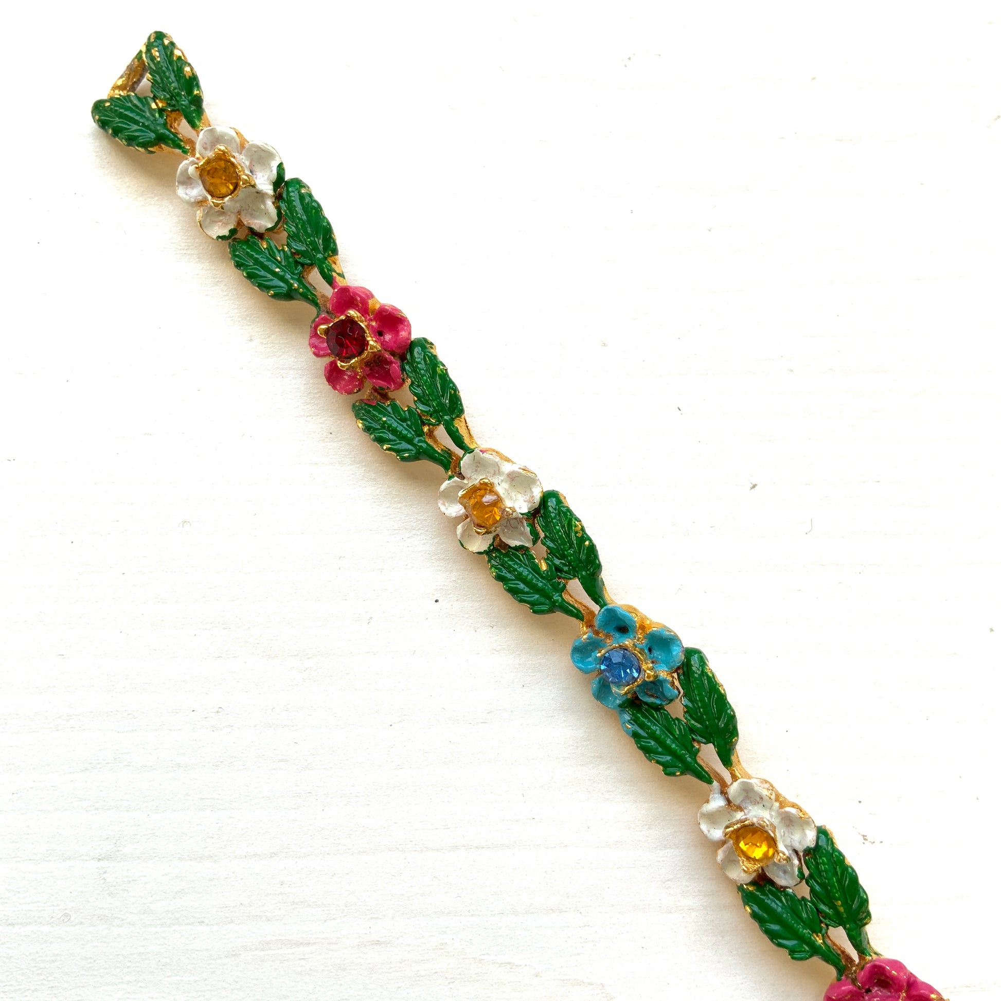 A delicate enamel bracelet adorned with rows of pink, pale blue and white flowers. ピンク、水色、白のお花が並んだエナメルのブレスレット。