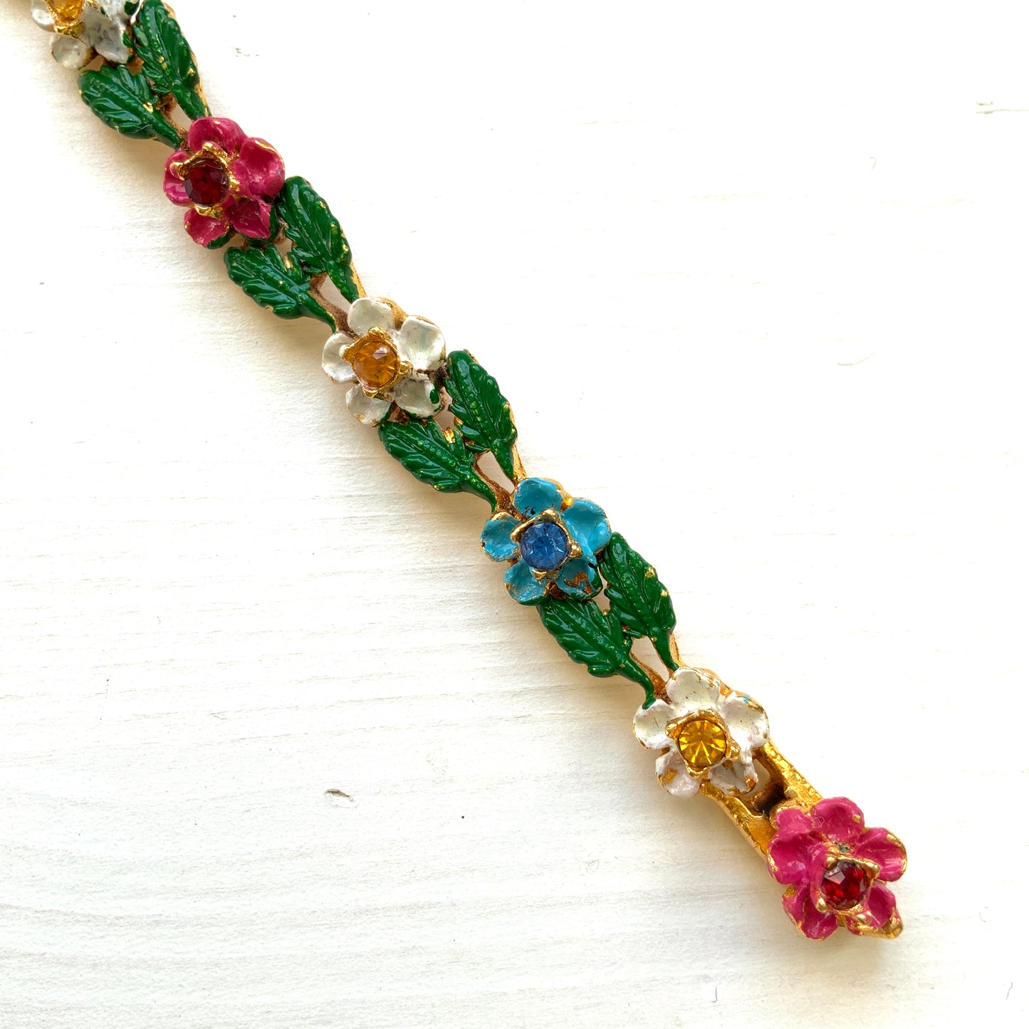 A delicate enamel bracelet adorned with rows of pink, pale blue and white flowers. ピンク、水色、白のお花が並んだエナメルのブレスレット。