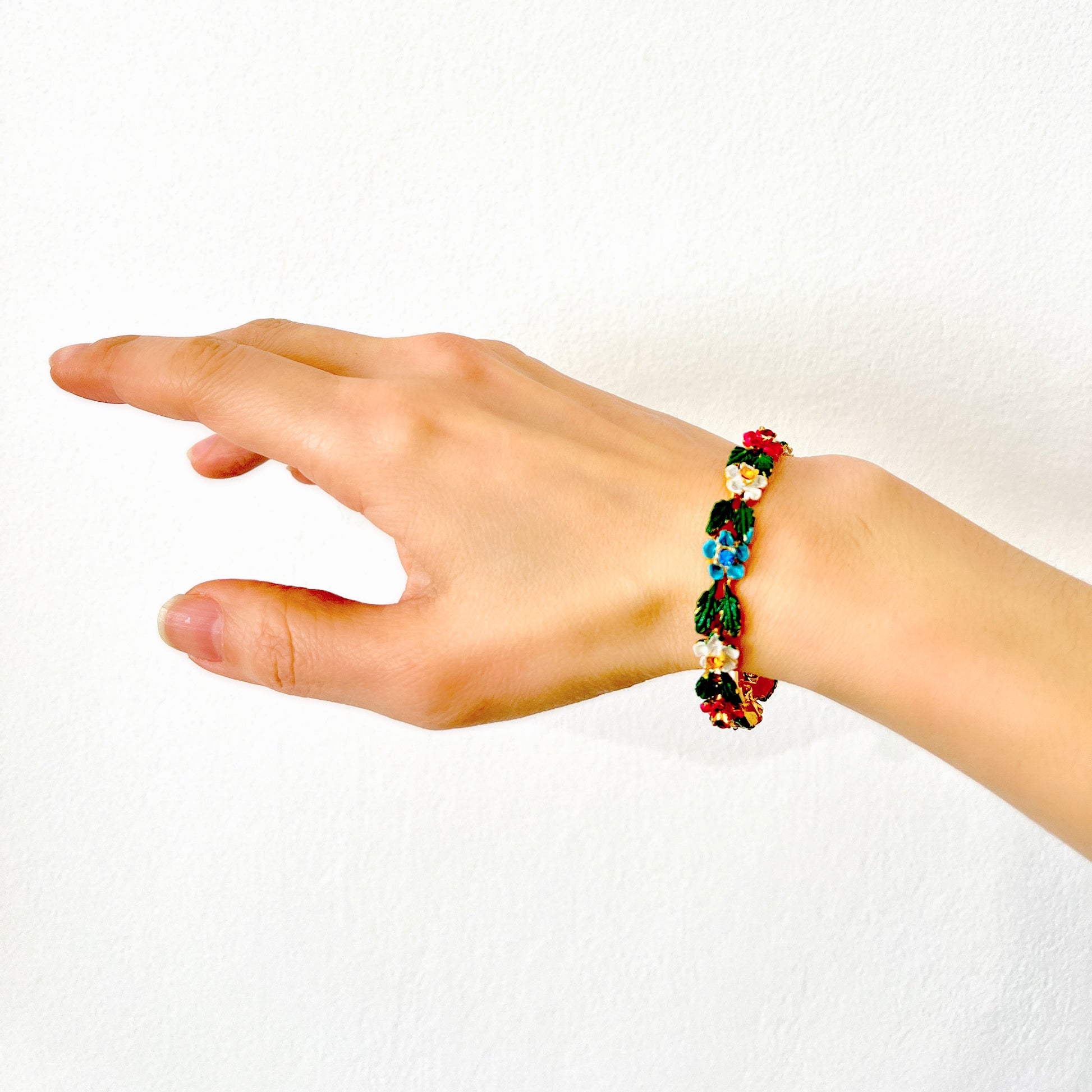 A delicate enamel bracelet adorned with rows of pink, pale blue and white flowers. ピンク、水色、白のお花が並んだエナメルのブレスレット。