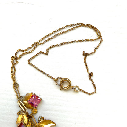 A delicate necklace featuring gold-tone leaves set with pink square glass stones. ゴールドトーンのリーフにピンクのスクエアガラスをあしらったネックレス。