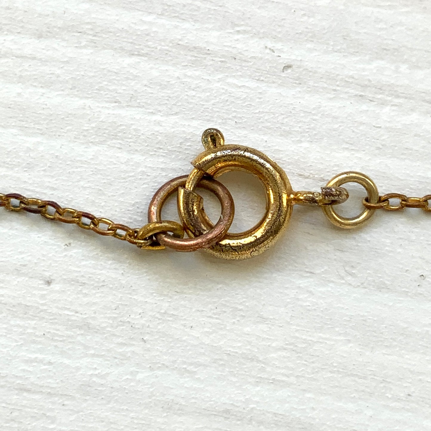 A delicate necklace featuring gold-tone leaves set with pink square glass stones. ゴールドトーンのリーフにピンクのスクエアガラスをあしらったネックレス。