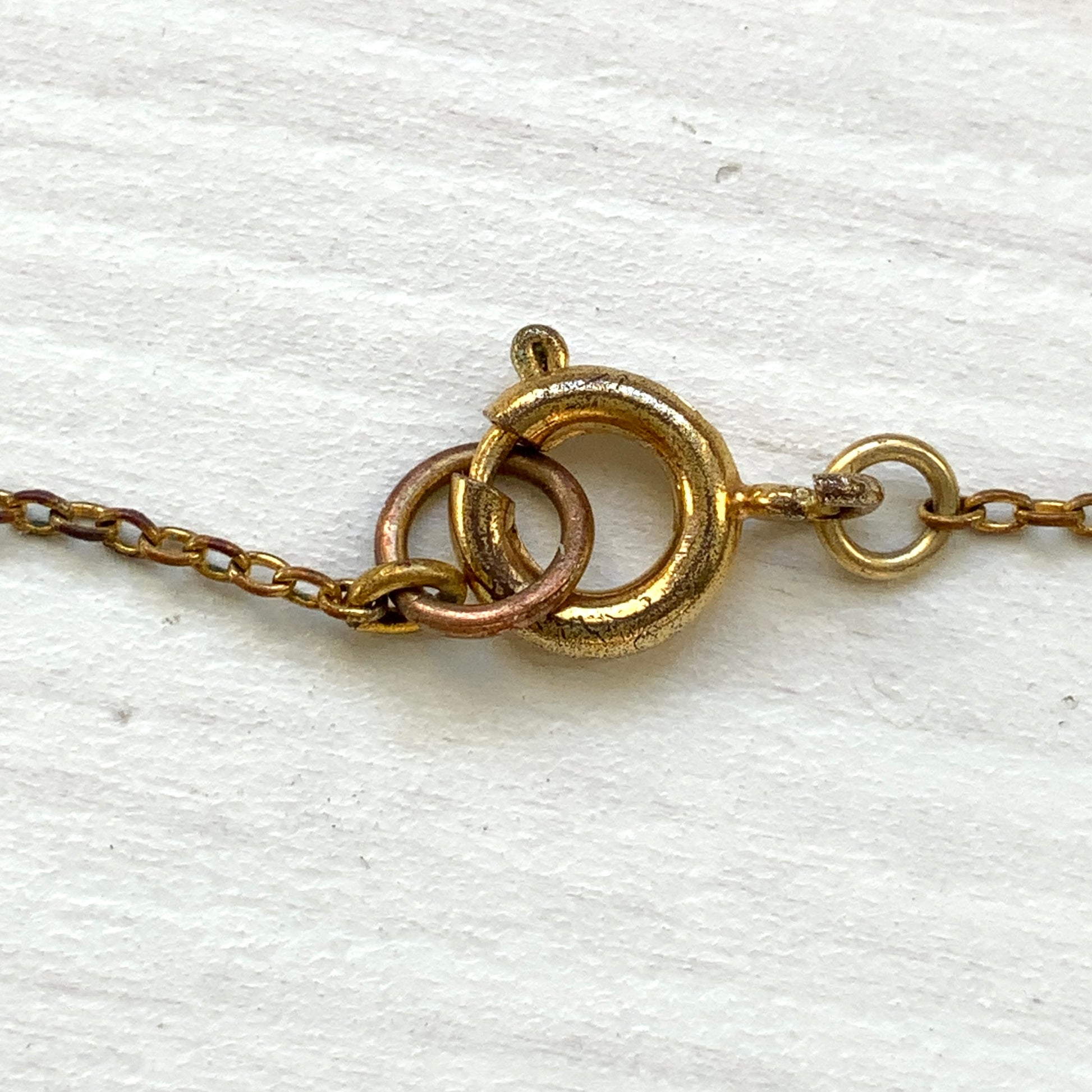 A delicate necklace featuring gold-tone leaves set with pink square glass stones. ゴールドトーンのリーフにピンクのスクエアガラスをあしらったネックレス。