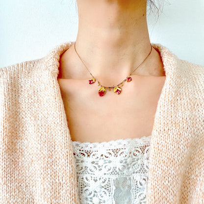 A delicate necklace featuring gold-tone leaves set with pink square glass stones. ゴールドトーンのリーフにピンクのスクエアガラスをあしらったネックレス。