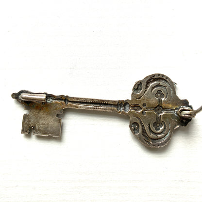A decorative vintage key brooch featuring a crown and crest motif in a beautifully classical design. 王冠と紋章のモチーフ、クラシカルでデコラティブなデザインが素敵な鍵ブローチ。 