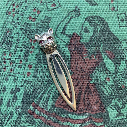 A cute cat's head peeks out from your book — a silver bookmark with a touch of charm.  かわいい猫の頭が本からのぞく、シルバー製のブックマーク。