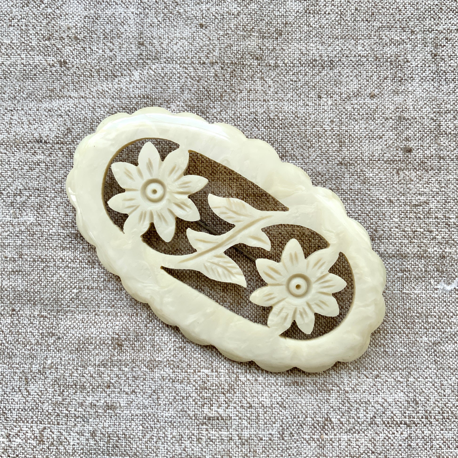 This vintage brooch is crafted from ivory-coloured celluloid in an openwork floral design. アイボリーカラーのセルロイドで作られた、オープンワークのフラワーブローチ。 