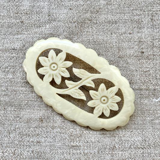 This vintage brooch is crafted from ivory-coloured celluloid in an openwork floral design. アイボリーカラーのセルロイドで作られた、オープンワークのフラワーブローチ。 