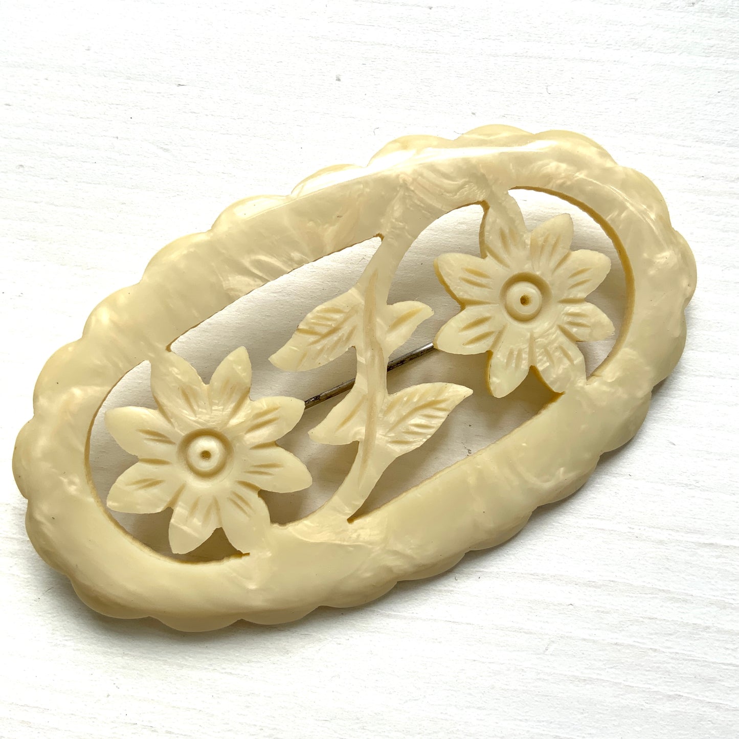 This vintage brooch is crafted from ivory-coloured celluloid in an openwork floral design. アイボリーカラーのセルロイドで作られた、オープンワークのフラワーブローチ。 