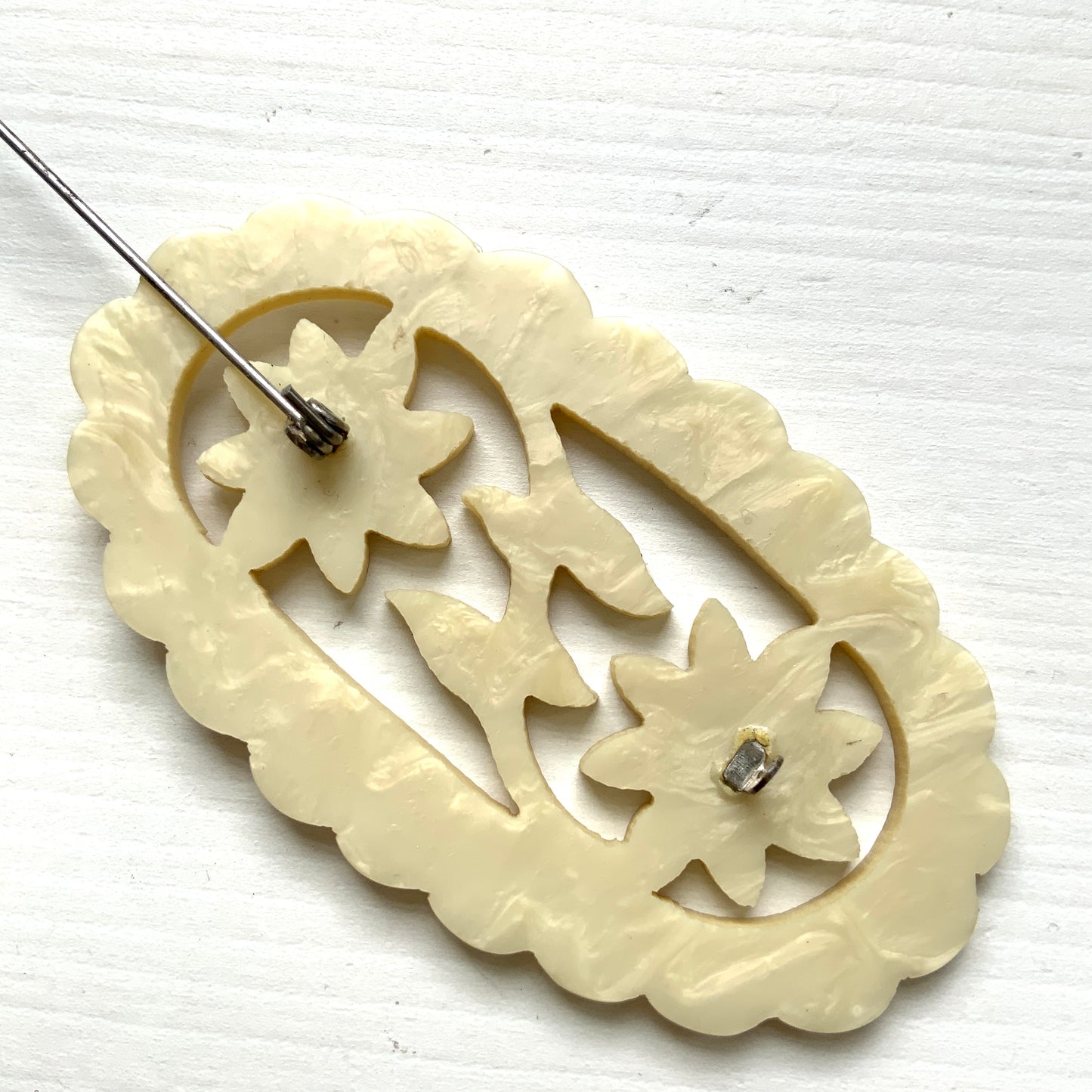 This vintage brooch is crafted from ivory-coloured celluloid in an openwork floral design. アイボリーカラーのセルロイドで作られた、オープンワークのフラワーブローチ。 