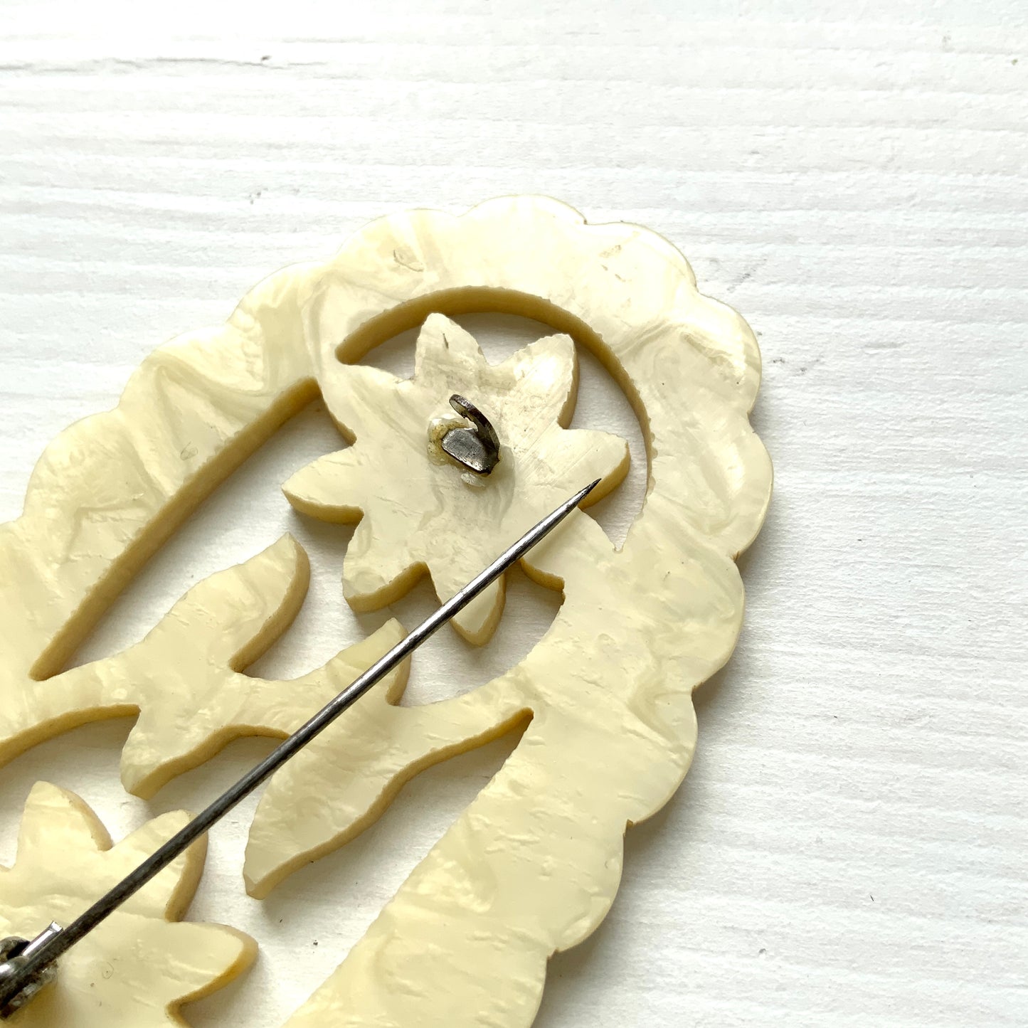 This vintage brooch is crafted from ivory-coloured celluloid in an openwork floral design. アイボリーカラーのセルロイドで作られた、オープンワークのフラワーブローチ。 