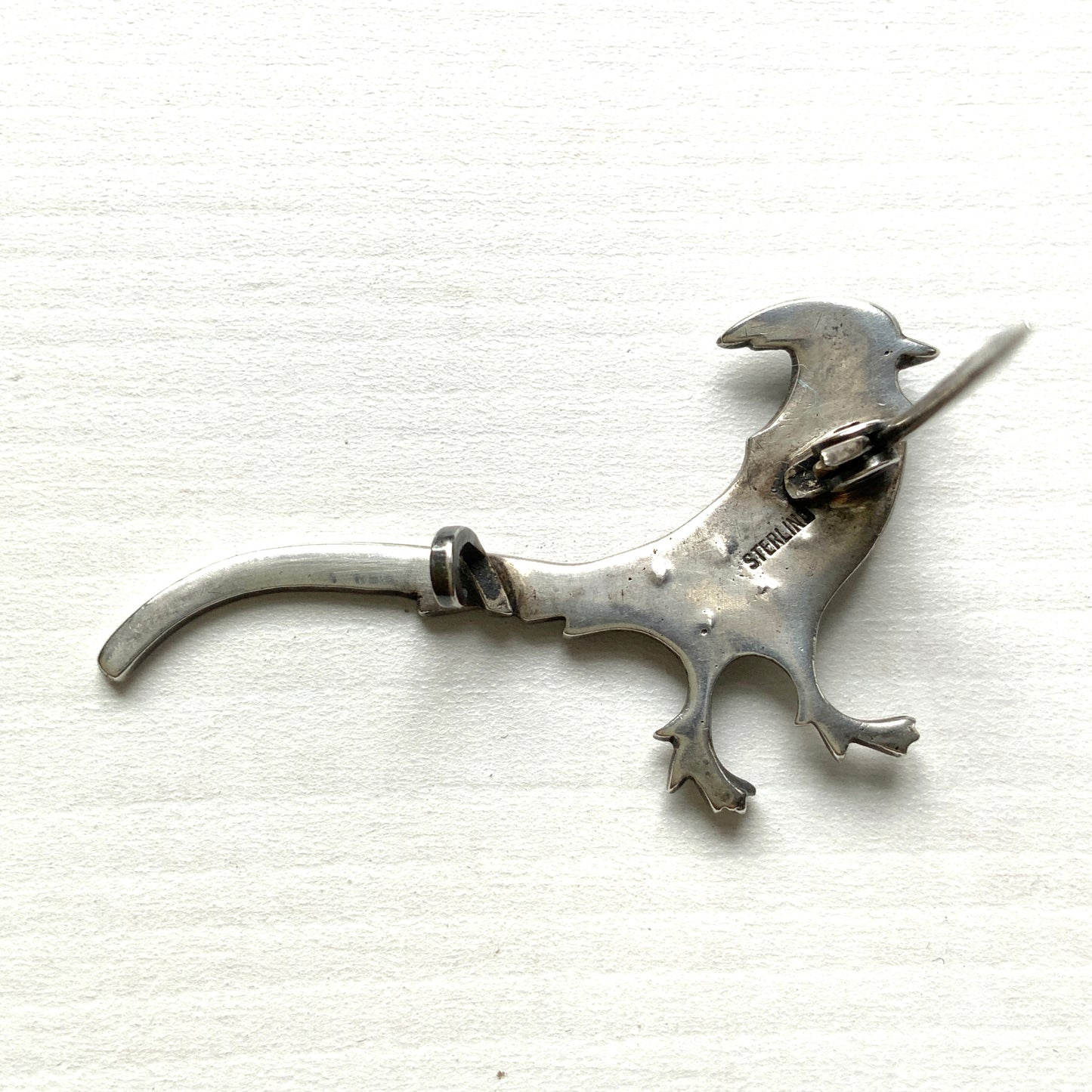 A sterling silver pheasant brooch featuring a beautiful enamel gradient shifting from blue to green.  ブルーからグリーンへと移ろうエナメルのグラデーションが美しい、雉モチーフのシルバーブローチ。