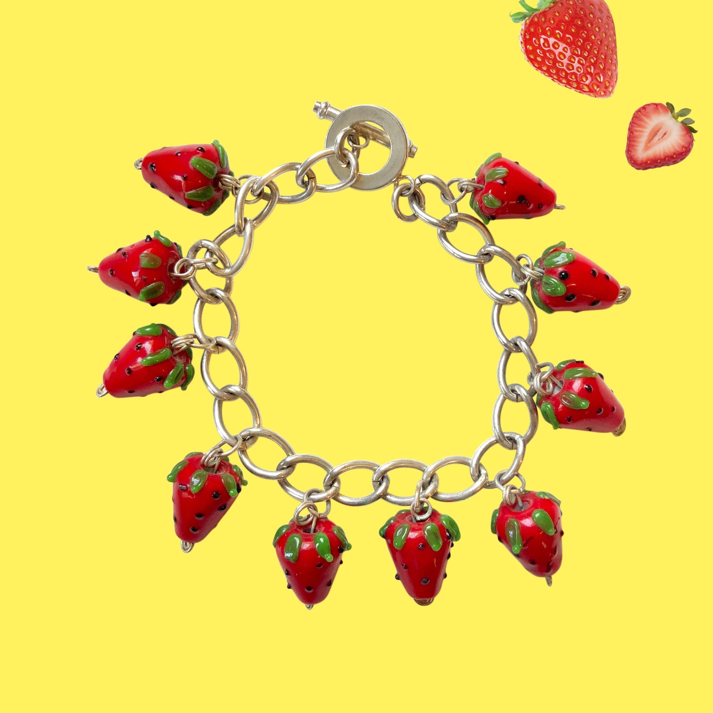 A bracelet with glass strawberry charms that sway from a silver-tone chain. ガラスのストロベリーチャームが揺れるブレスレット。