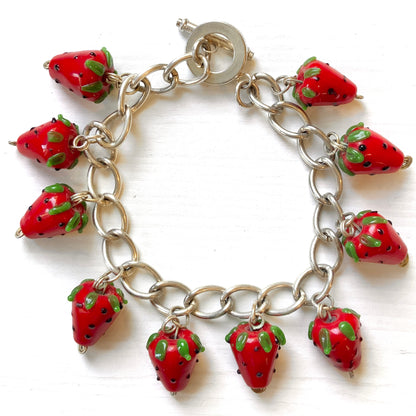 A bracelet with glass strawberry charms that sway from a silver-tone chain. ガラスのストロベリーチャームが揺れるブレスレット。