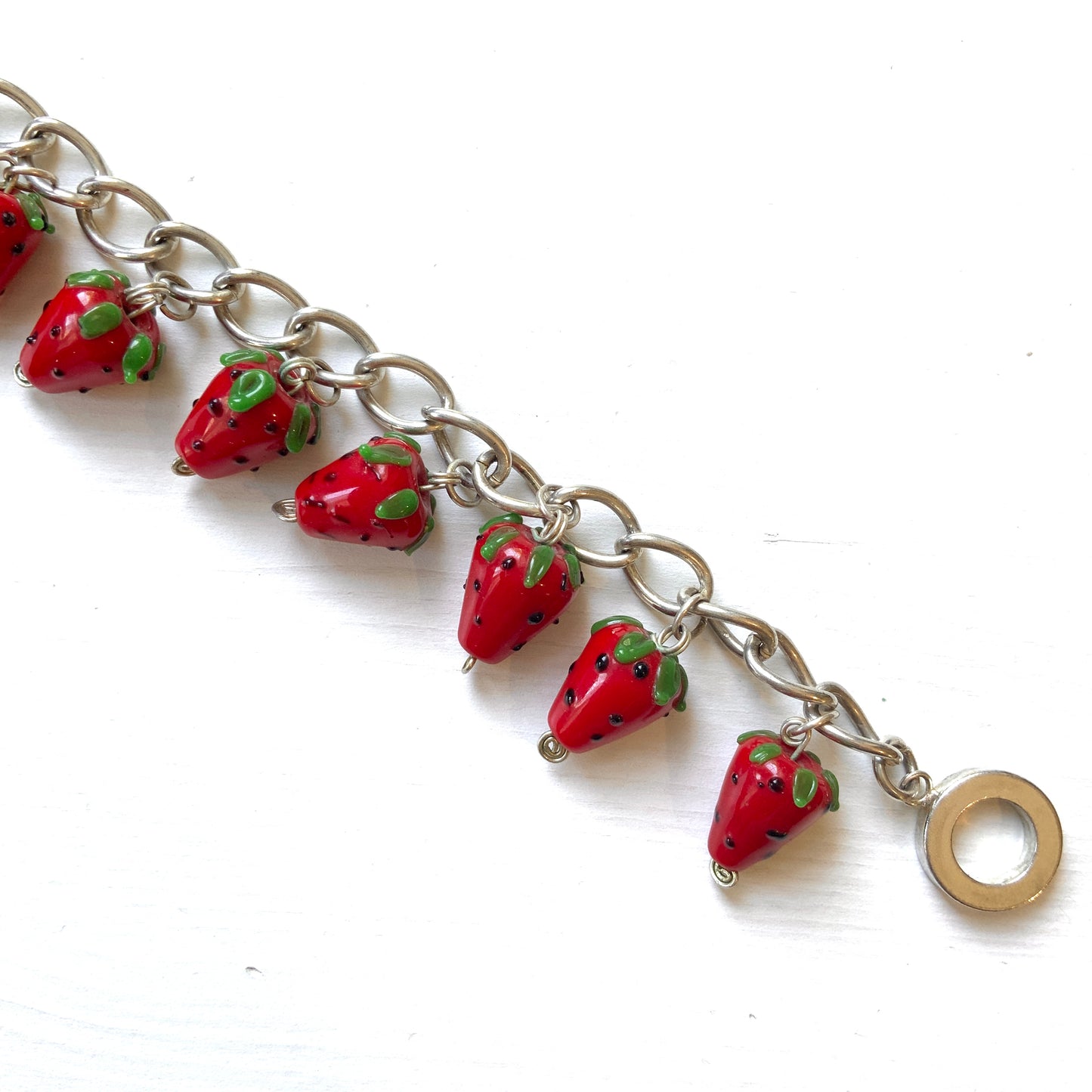 A bracelet with glass strawberry charms that sway from a silver-tone chain. ガラスのストロベリーチャームが揺れるブレスレット。