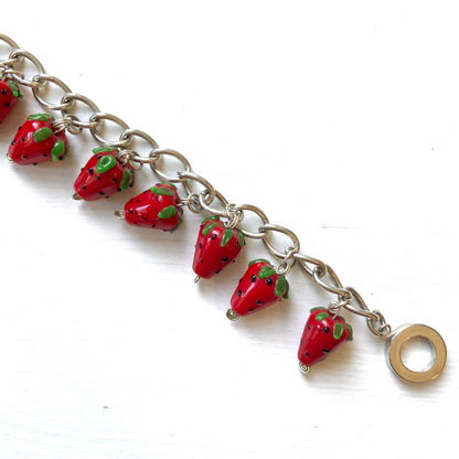 A bracelet with glass strawberry charms that sway from a silver-tone chain. ガラスのストロベリーチャームが揺れるブレスレット。