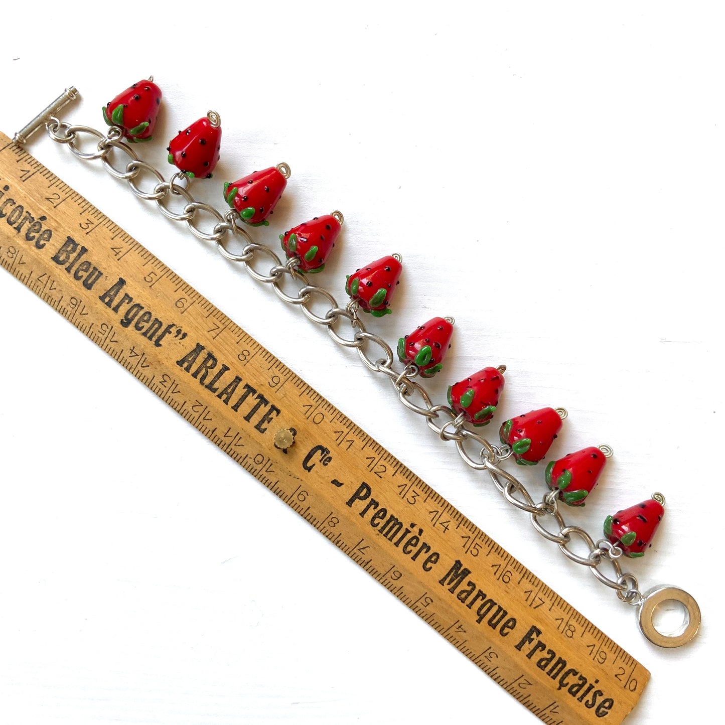 A bracelet with glass strawberry charms that sway from a silver-tone chain. ガラスのストロベリーチャームが揺れるブレスレット。