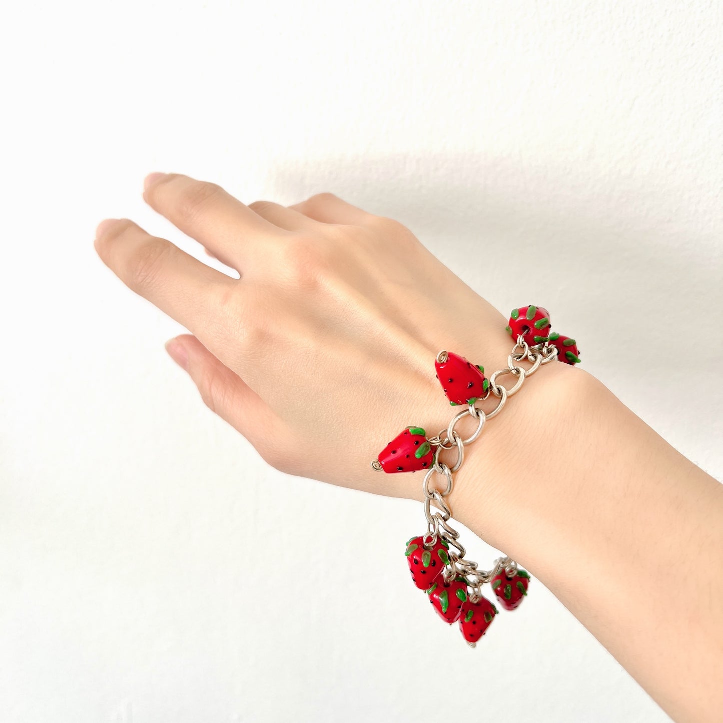 A bracelet with glass strawberry charms that sway from a silver-tone chain. ガラスのストロベリーチャームが揺れるブレスレット。