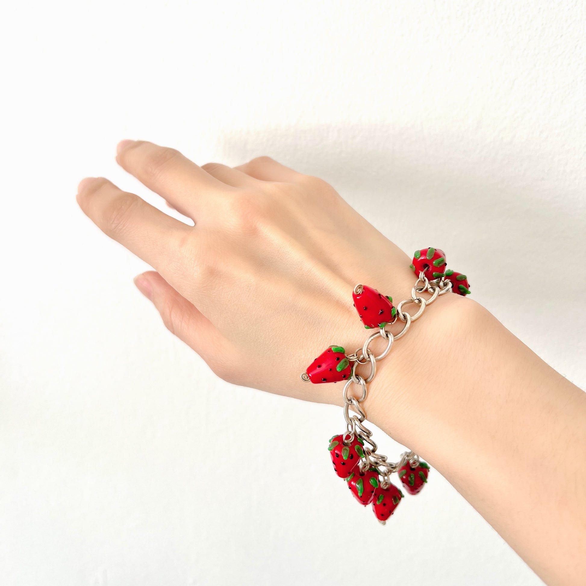 A bracelet with glass strawberry charms that sway from a silver-tone chain. ガラスのストロベリーチャームが揺れるブレスレット。