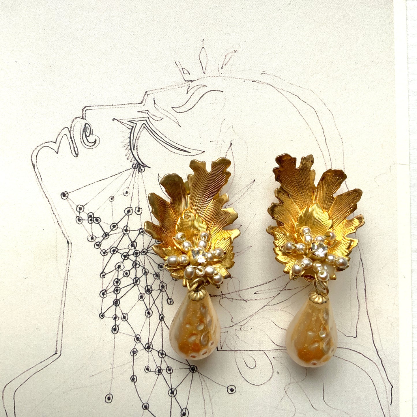 Clip-on earrings featuring gold-tone leaves, tiny pearl flowers, and dangling teardrop glass pearls. ゴールドトーンの美しいリーフに小粒パールのお花と、ティアドロップのグラスパールがゆれるクリップイヤリング。