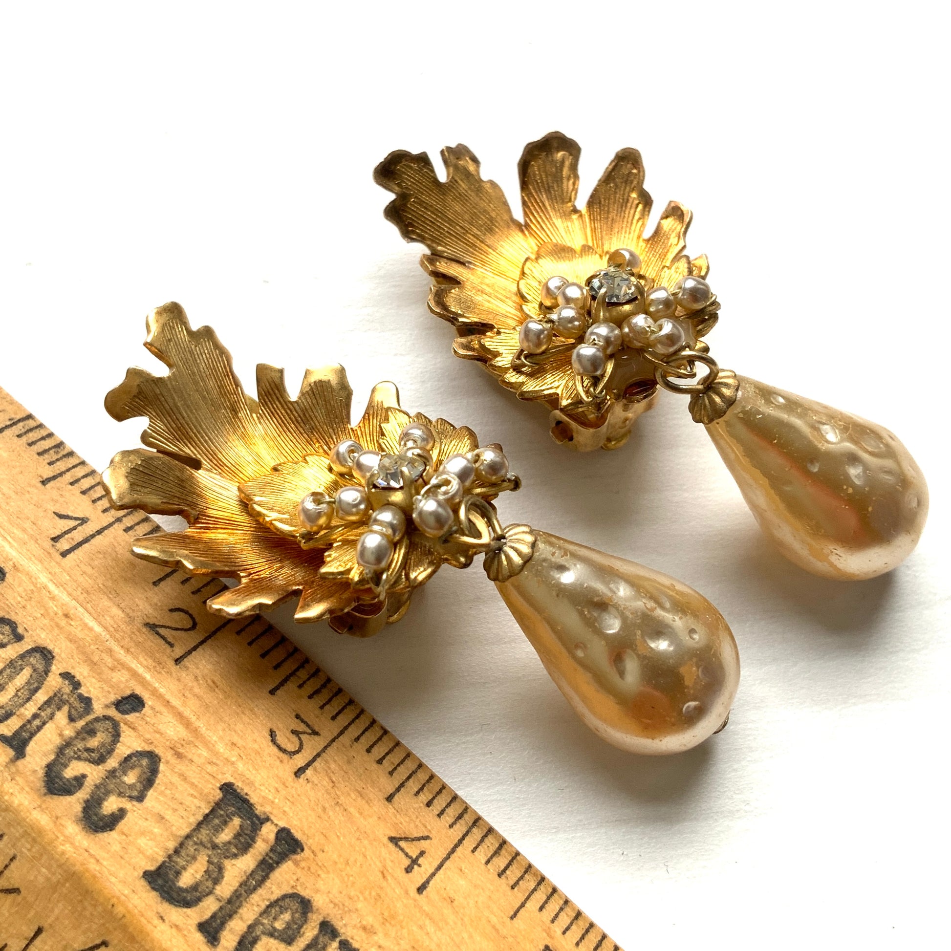 Clip-on earrings featuring gold-tone leaves, tiny pearl flowers, and dangling teardrop glass pearls. ゴールドトーンの美しいリーフに小粒パールのお花と、ティアドロップのグラスパールがゆれるクリップイヤリング。