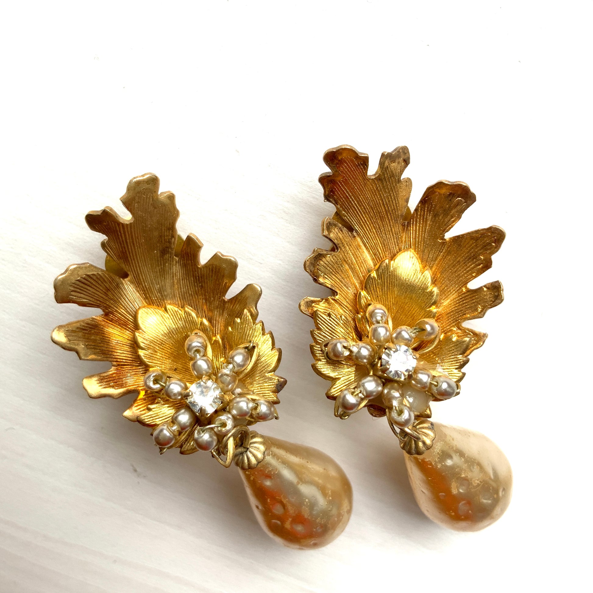 Clip-on earrings featuring gold-tone leaves, tiny pearl flowers, and dangling teardrop glass pearls. ゴールドトーンの美しいリーフに小粒パールのお花と、ティアドロップのグラスパールがゆれるクリップイヤリング。