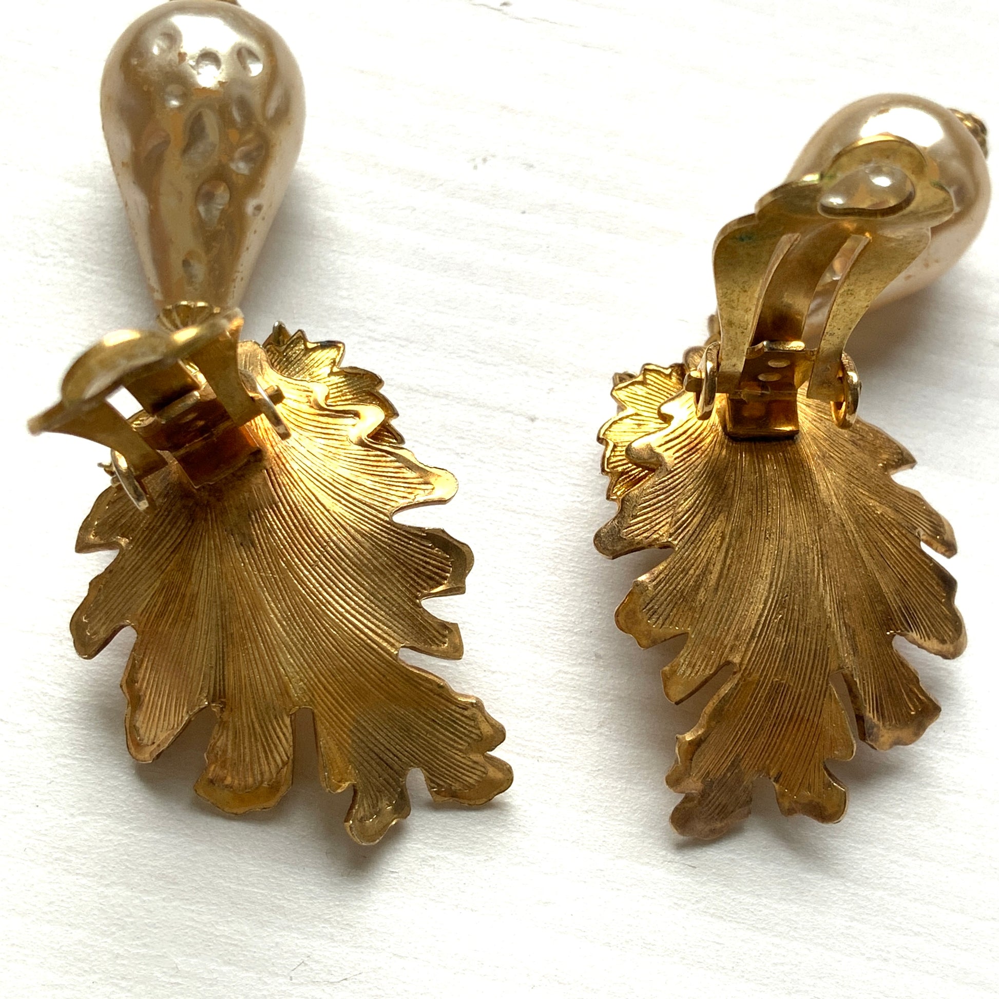 Clip-on earrings featuring gold-tone leaves, tiny pearl flowers, and dangling teardrop glass pearls. ゴールドトーンの美しいリーフに小粒パールのお花と、ティアドロップのグラスパールがゆれるクリップイヤリング。