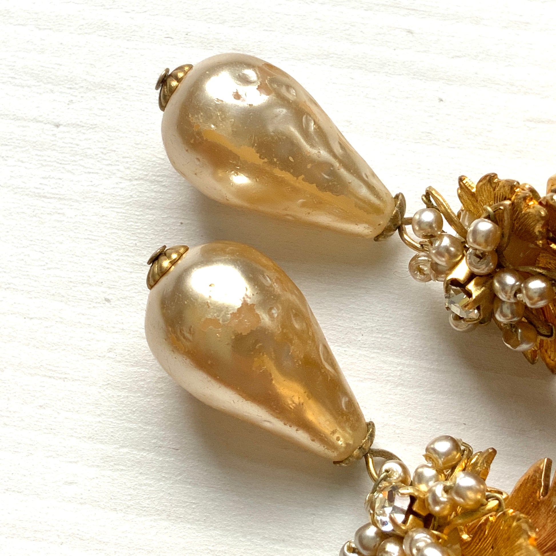 Clip-on earrings featuring gold-tone leaves, tiny pearl flowers, and dangling teardrop glass pearls. ゴールドトーンの美しいリーフに小粒パールのお花と、ティアドロップのグラスパールがゆれるクリップイヤリング。