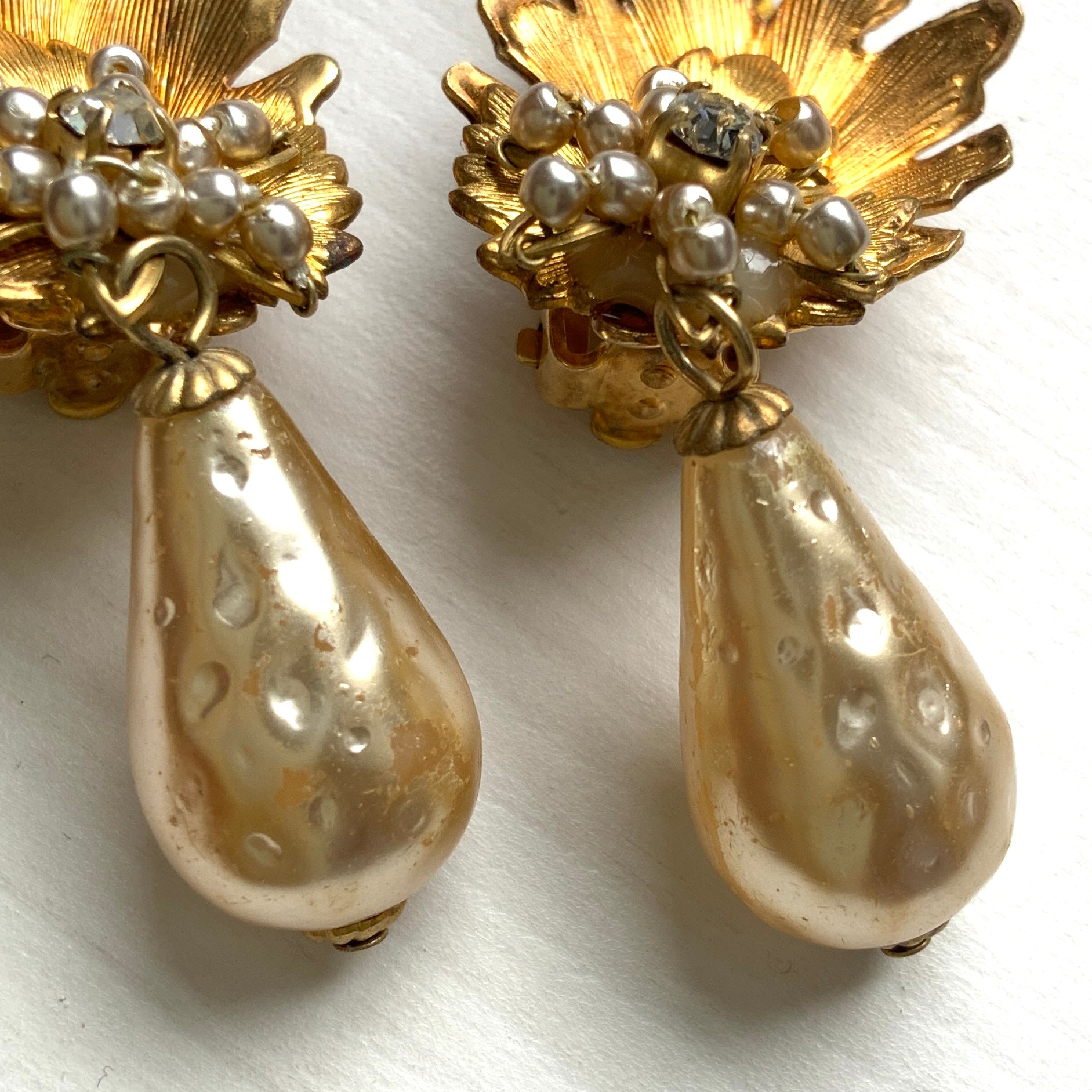 Clip-on earrings featuring gold-tone leaves, tiny pearl flowers, and dangling teardrop glass pearls. ゴールドトーンの美しいリーフに小粒パールのお花と、ティアドロップのグラスパールがゆれるクリップイヤリング。